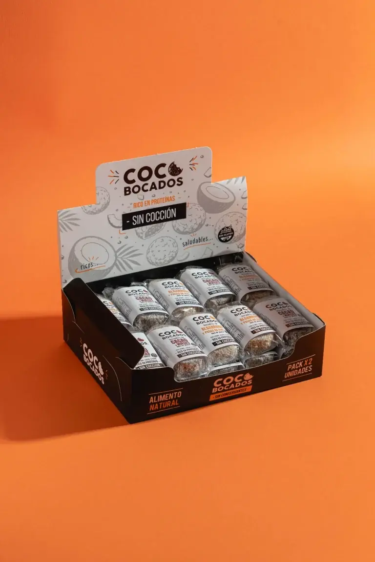 Exhibidor de Coco Bocados con envases individuales sobre fondo naranja.