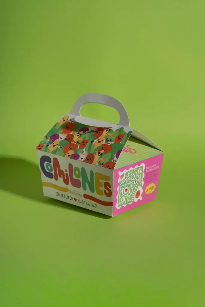Caja de Comilones con asa e ilustraciones de alimentos sobre fondo verde.